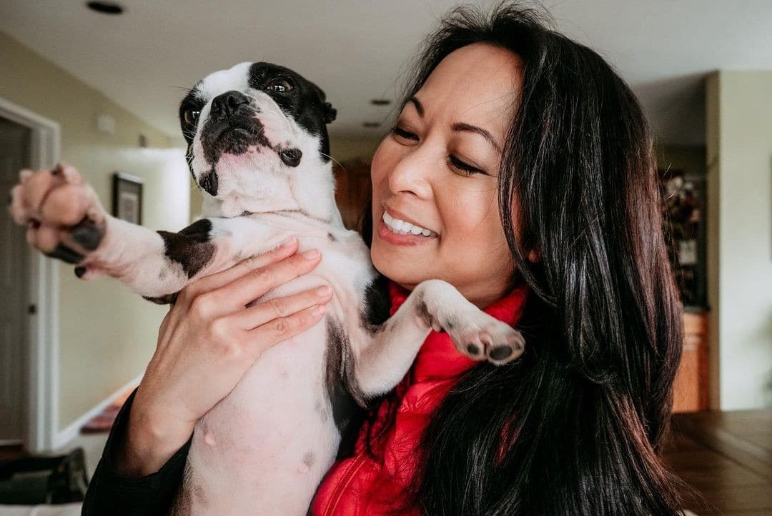 A woman holding a Boston terrier in her arms, illustrating how dogs helped people survive 2020.