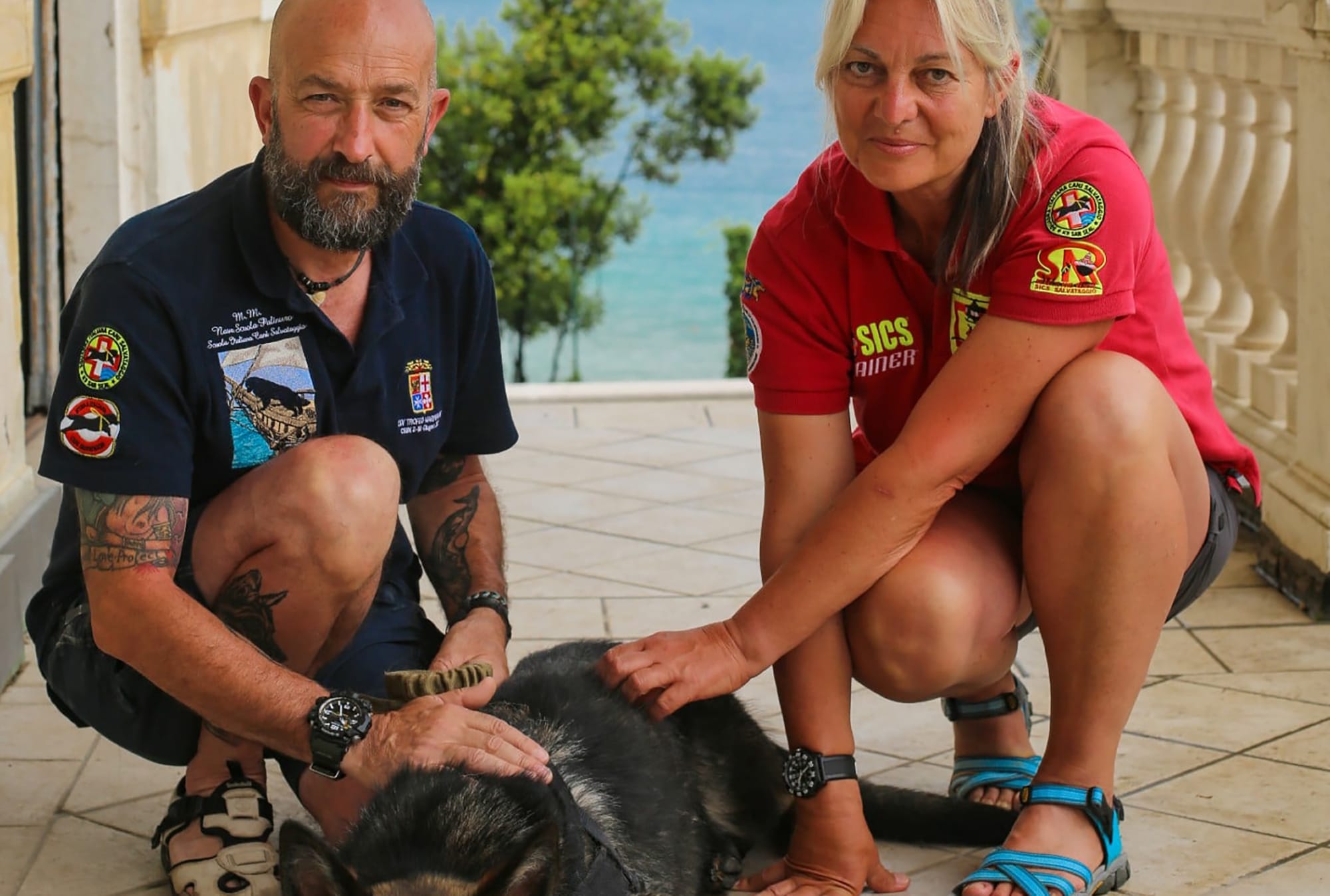 A man and woman kneeling down next to a dog with extraordinary jobs.