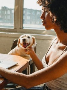 A woman sitting at a table with a dog.