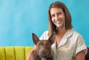A woman teaches her brown dog words while sitting on a couch.