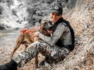 A woman in camouflage poses with her dog in Ukraine, supporting Heroes Helping Animals.