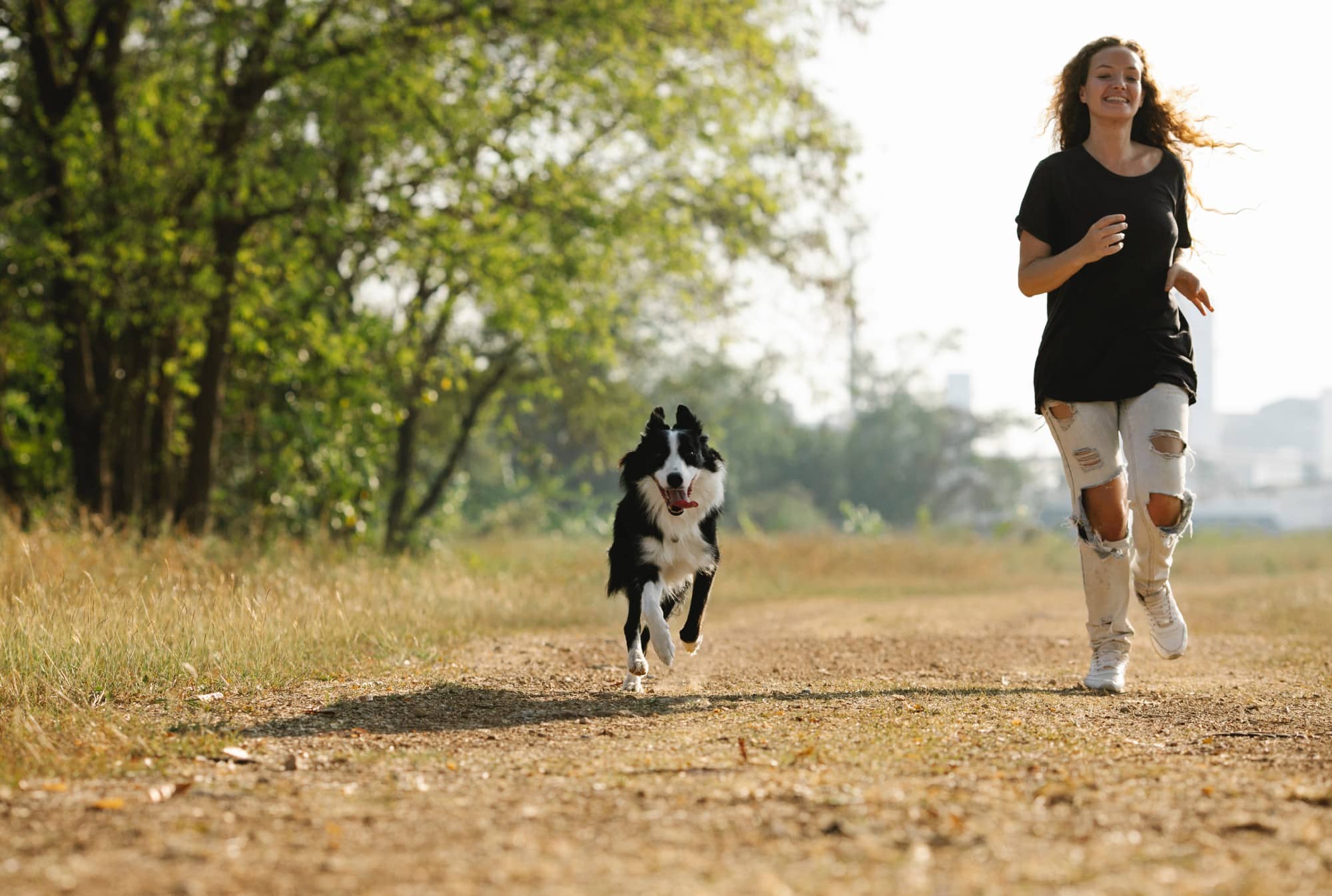 A woman jogging with her dog on a dirt road, booked via a Rent a Backyard App.