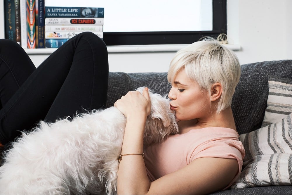 dog on couch giving kisses to a woman