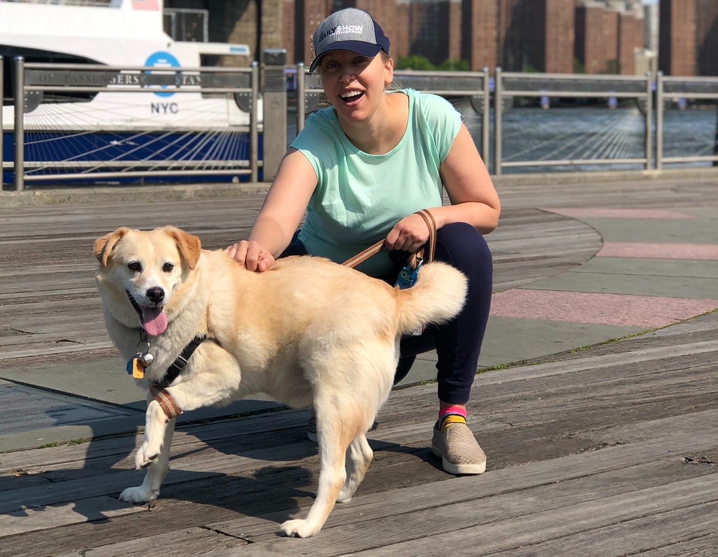 A woman, appearing as a Zen Master, kneeling on a boardwalk with a dog, imparting life lessons.